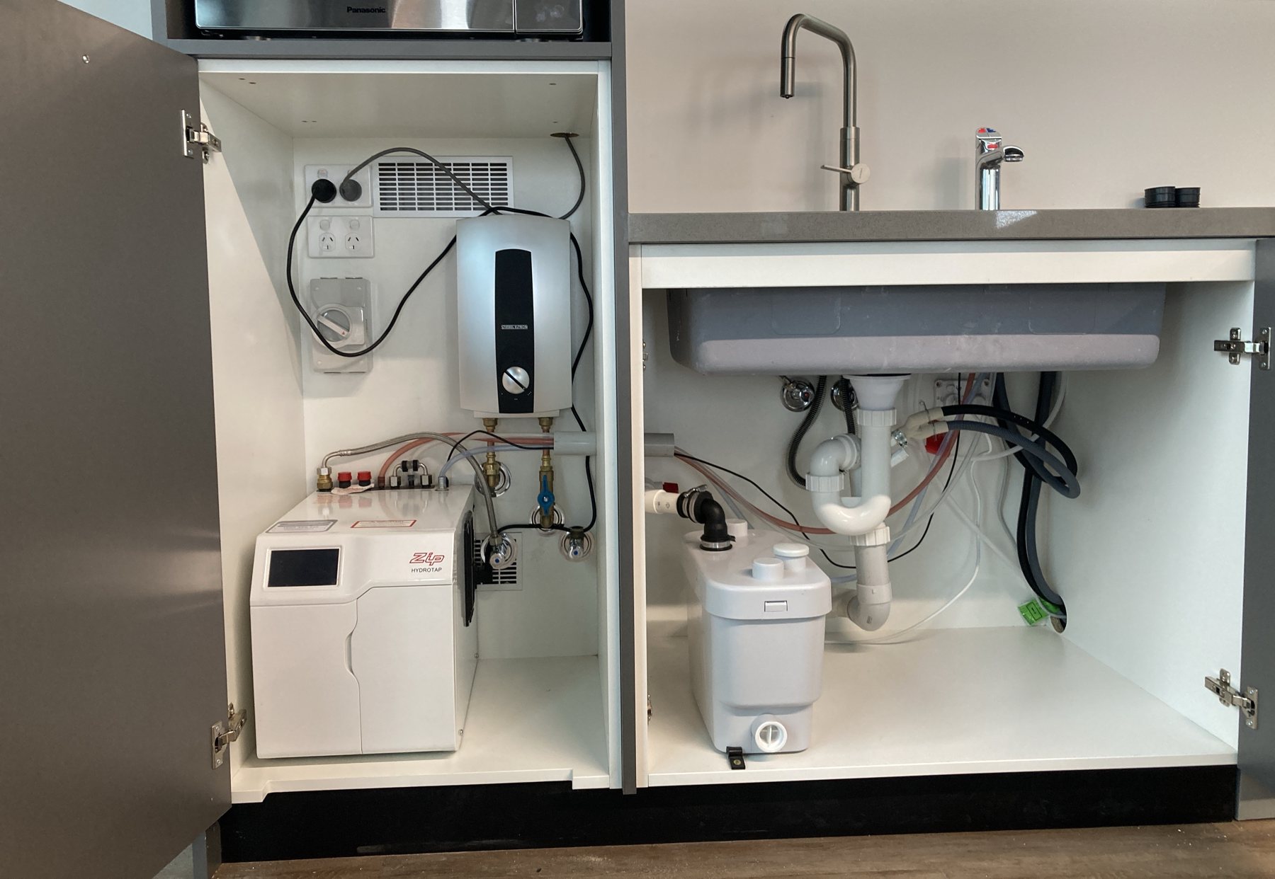 Kitchenette hot water installation — instantaneous water heater, filtered boiling water unit and under-sink macerator.